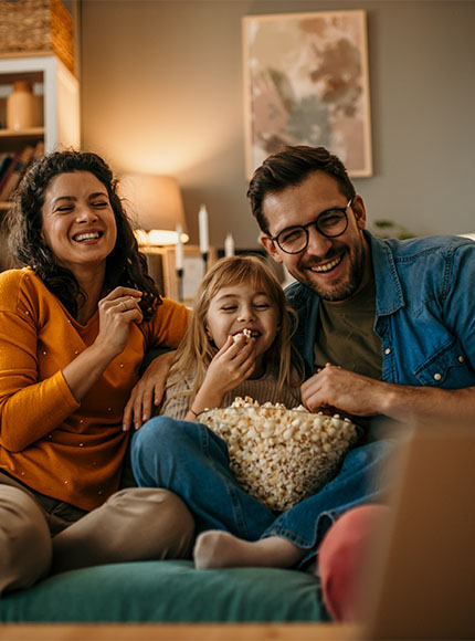 family eating popcorn on couch watching a movie